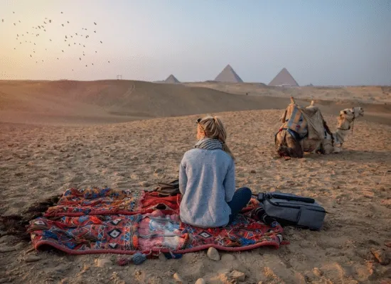 Woman watches sunset at the Giza Pyramids, Egypt Day Tours