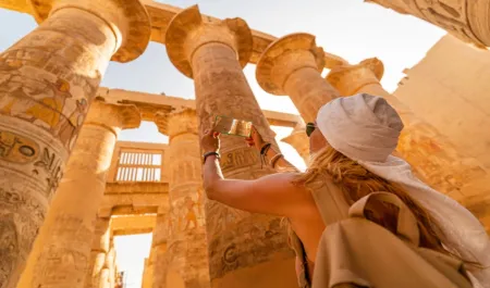 Female tourist walks between Pillars of the Great Hypostyle Hall from Karnak Temple, Travel Tour to Egypt
